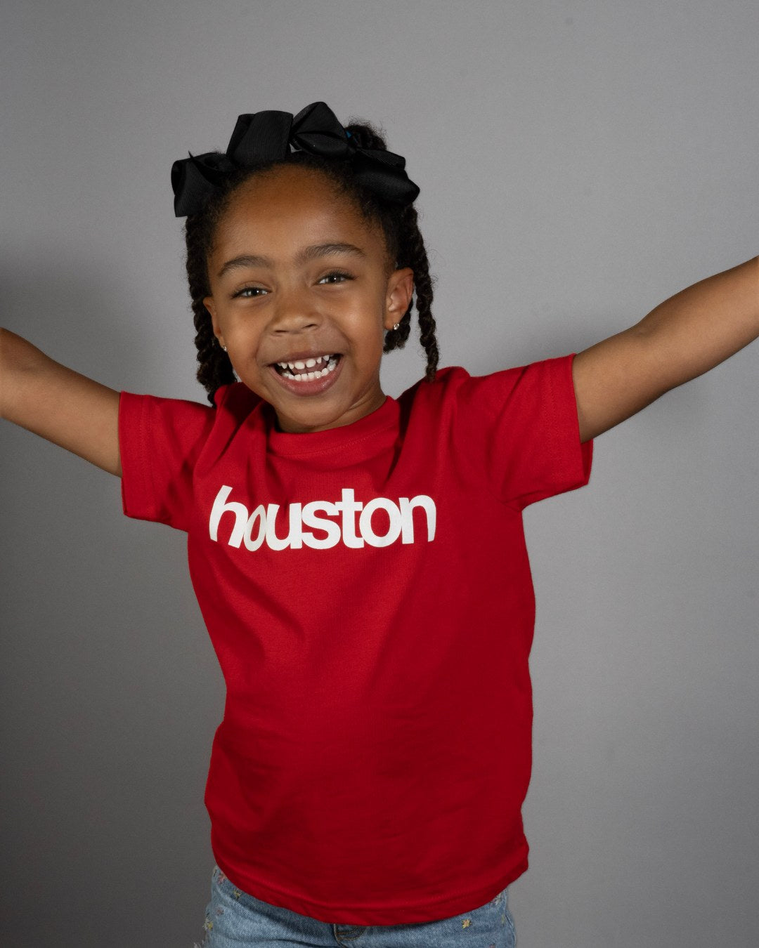Smiling kid in a red premiumgoods. houston. tee, arms out